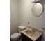 Compact bathroom features a sink, toilet, and round mirror at 11323 E Cimmarron Dr, Englewood, CO 80111