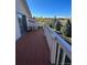 Spacious wood deck with white railing and sliding door, overlooking lush trees and field at 11323 E Cimmarron Dr, Englewood, CO 80111