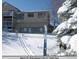 Exterior view of the home in winter with snow, skis and a snowy tree at 11323 E Cimmarron Dr, Englewood, CO 80111