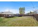 Large grassy backyard featuring a trampoline, deck with hot tub, shed, and wood fence at 3057 S Fox St, Englewood, CO 80110