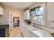 Bright kitchen with white cabinetry, a double basin sink, a window, and a view into laundry/storage room at 1701 W 50Th Ave, Denver, CO 80221