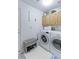 Functional laundry room with washer, dryer, overhead cabinets and access door at 12935 Lake Circle Dr, Thornton, CO 80241