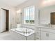 A luxurious bathroom featuring a soaking tub with white marble tile, dual vanities, and a large picture window at 4978 Hickory Oaks St, Castle Rock, CO 80104