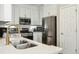 Modern kitchen with stainless steel appliances, gold faucet, white cabinets and marble countertops at 3178 Geneva Ct, Denver, CO 80238