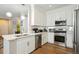 Updated kitchen with stainless steel appliances, white cabinets, and a stylish backsplash overlooking living area at 3178 Geneva Ct, Denver, CO 80238