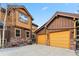 Exterior view of brown and yellow home featuring two garage doors with stone accents and manicured landscaping at 200 Rachel Ln, Breckenridge, CO 80424