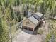 Aerial view showing the two-car garage, home and large decks, surrounded by trees at 10469 Christopher Dr, Conifer, CO 80433