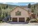 Two-story home featuring a two-car garage and elevated deck access, nestled against a mountainside at 10469 Christopher Dr, Conifer, CO 80433