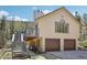 Exterior featuring a large deck with stairs, two-car garage, mature trees, and a charming property at 10469 Christopher Dr, Conifer, CO 80433