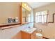 Well-lit bathroom featuring a sink, mirror, and a toilet adjacent to a window at 1304 S Harlan St, Lakewood, CO 80232