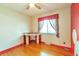 Bedroom features hardwood floors, a built-in desk, and bright window with colorful curtains at 1304 S Harlan St, Lakewood, CO 80232