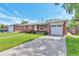 Beautiful brick home with a well-kept lawn, mature trees, and a convenient driveway to the garage at 1304 S Harlan St, Lakewood, CO 80232