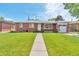 Charming brick home featuring a well-manicured lawn and walkway leading to the front door at 1304 S Harlan St, Lakewood, CO 80232