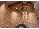 Ornate chandelier hanging in the foyer with brick walls, arched doorway, and warm lighting at 9617 S Shadow Hill Cir, Lone Tree, CO 80124