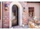 Elegant front door with brick exterior, arched frame, decorative lanterns, and well-manicured potted plants at 9617 S Shadow Hill Cir, Lone Tree, CO 80124