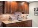Basement wet bar with custom cabinets, granite counters, brick backsplash, and ample storage at 9617 S Shadow Hill Cir, Lone Tree, CO 80124