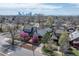Aerial view of a residential neighborhood with mature trees and a distant city skyline at 3311 N York St, Denver, CO 80205