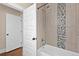 Modern bathroom showcasing a tub/shower combo with decorative tile and an open door at 3311 N York St, Denver, CO 80205