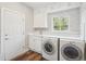 Modern laundry room with a window, washer, dryer, and white cabinets at 1474 S Uinta Ct, Denver, CO 80231