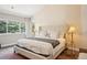 Main bedroom featuring a bed with a padded headboard, two lamps, and large window at 1474 S Uinta Ct, Denver, CO 80231