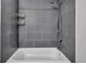 Close up on a modern white bathtub surrounded by gray tiles with shower fixtures at 8905 Field St # 91, Westminster, CO 80021