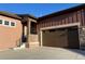 Charming home exterior with stone accents, wood siding, large garage door, and a well-manicured front yard at 3598 New Haven Cir, Castle Rock, CO 80109