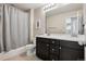 Well-lit bathroom with dual sinks, dark cabinetry, and shower with gray tiling offers comfort and style at 655 Tiger Lily Way, Highlands Ranch, CO 80126