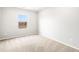 Bright bedroom featuring neutral carpet, a large window offering outdoor views, and freshly painted walls at 8840 Sedalia St, Commerce City, CO 80022