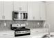 Close-up on the kitchen features modern appliances and a gray backsplash at 8840 Sedalia St, Commerce City, CO 80022