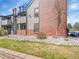 Low angle view of condo showing brick accents, lawn, and chimney at 11985 E Harvard Ave # 108, Aurora, CO 80014
