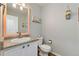 Cozy half-bathroom features a pedestal sink, peach framed mirror, and stylish details for added convenience at 22142 E Belleview Place, Aurora, CO 80015