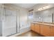 Bright bathroom featuring a soaking tub, a separate shower and dual sinks with wooden cabinetry at 11373 Kearney Way, Thornton, CO 80233