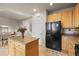 Well-lit kitchen featuring wood cabinets, modern black appliances, and a kitchen island at 11373 Kearney Way, Thornton, CO 80233