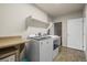 A laundry room equipped with modern appliances, overhead shelving, and tiled flooring at 11373 Kearney Way, Thornton, CO 80233