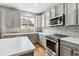 Modern kitchen with gray cabinets, stone backsplash, stainless steel appliances, and hardwood floors at 1466 Turnberry Dr, Castle Rock, CO 80104