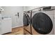 Bright laundry room features modern Samsung washer and dryer on wood-look floors, and a white sink with stylish backsplash at 1466 Turnberry Dr, Castle Rock, CO 80104