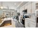 Modern kitchen featuring stainless steel appliances, white cabinets, and gray wood floors at 6737 S Tempe Ct, Aurora, CO 80016