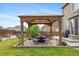 Charming backyard with a wooden gazebo, stone patio, and lush green lawn, ideal for outdoor gatherings at 12616 Jersey W Cir, Brighton, CO 80602