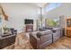 Bright living room featuring wood floors, fireplace, large windows and comfortable leather seating at 12616 Jersey W Cir, Brighton, CO 80602