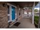 Inviting front porch with a brick accent, white railing, colorful planters and a vibrant blue door at 7334 S Moore St, Littleton, CO 80127