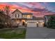 Charming two-story home featuring a three-car garage and covered porch, set against a stunning sunset backdrop at 21482 E Idyllwilde Dr, Parker, CO 80138