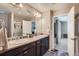 Bright bathroom featuring dual sinks, dark cabinets, large mirror and walk-in shower at 11709 Park South Ln, Parker, CO 80138
