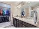 Bright bathroom featuring dual sinks, dark cabinets, large mirror and walk-in closet at 11709 Park South Ln, Parker, CO 80138