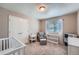 Neutral bedroom featuring a white crib, sitting chair, and a window with blinds at 11709 Park South Ln, Parker, CO 80138