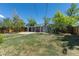 A spacious, grassy backyard features mature trees, a covered patio and a wooden fence at 967 Victor St, Aurora, CO 80011