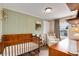 Charming Bedroom featuring a wooden crib, chair, and soft green wall at 3175 S Pennsylvania St, Englewood, CO 80113