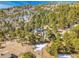 Mountain home with solar panels amidst trees, partially covered with snow and located on a sloping landscape at 312 Meadow View Dr, Evergreen, CO 80439