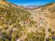 An aerial view showcases a hillside property nestled amongst pine trees with mountain views at 312 Meadow View Dr, Evergreen, CO 80439