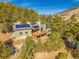 Aerial view of a home with solar panels and a deck, surrounded by lush trees and partial mountain views at 312 Meadow View Dr, Evergreen, CO 80439