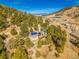 Scenic aerial view of a home nestled amongst the trees with solar panels on the roof and mountain views at 312 Meadow View Dr, Evergreen, CO 80439